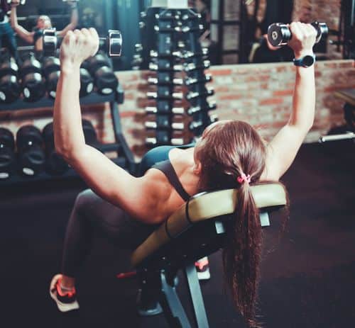 Premium Photo  Fit woman trains chest muscles doing bench press with  dumbbells in hands while lying on an incline bench in the gym